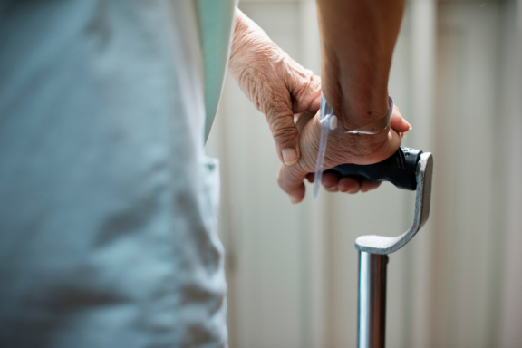 Close-up of an older adult holding a cane, highlighting mobility support and fall prevention.