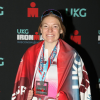 Samantha Crowley poses with her Ironman medal and flag at the finish line.