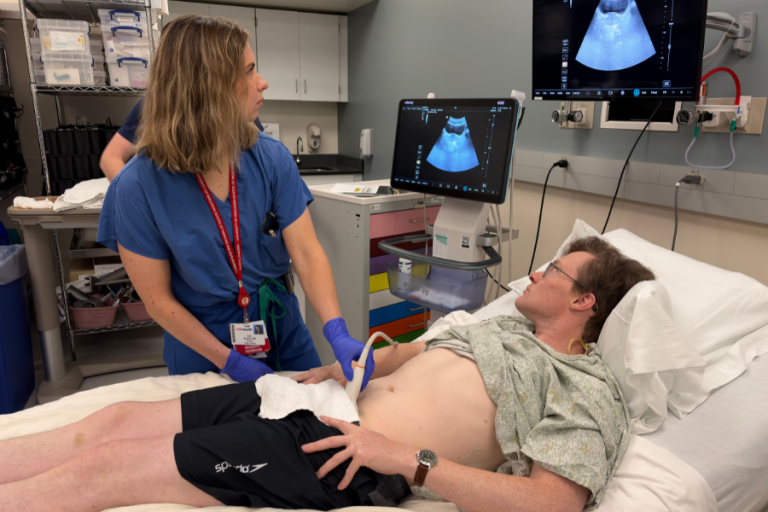 A resident practices lower abdominal ultrasound on a simulated patient.