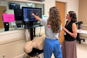 A resident practices abdominal ultrasound on a simulation manikin, with faculty instruction.