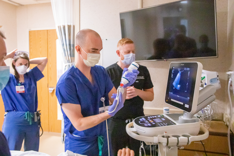 A resident practices abdominal ultrasound on a simulation manikin, with faculty instruction.